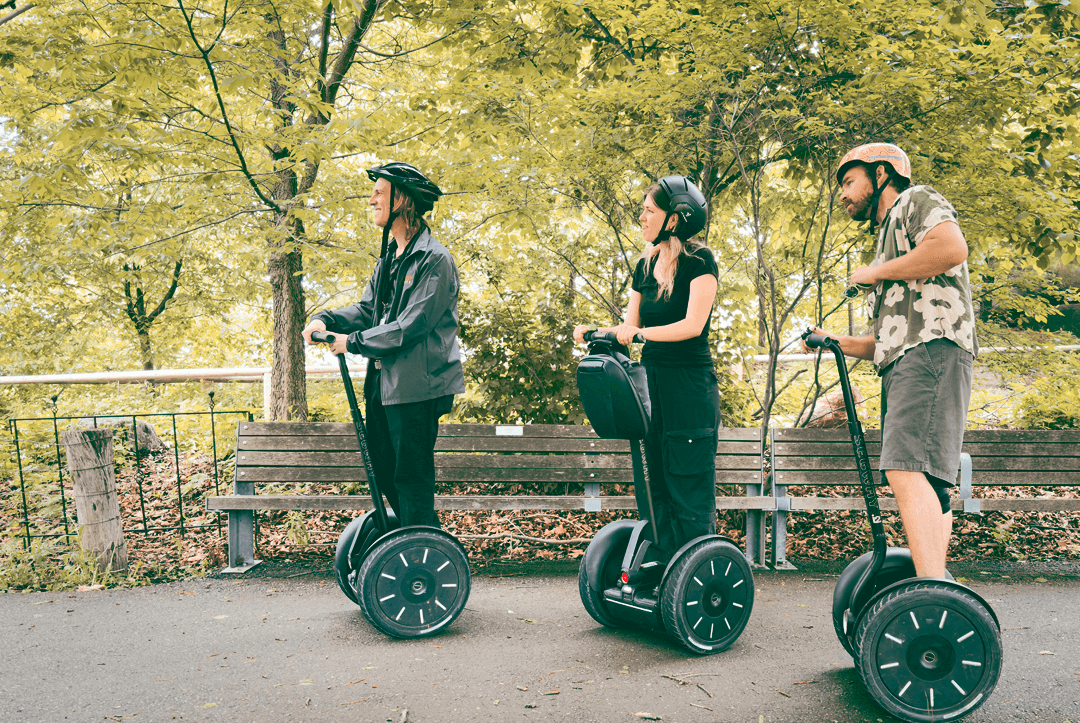 Three riders on Segways on a tree-lined path in Toronto's Canary District