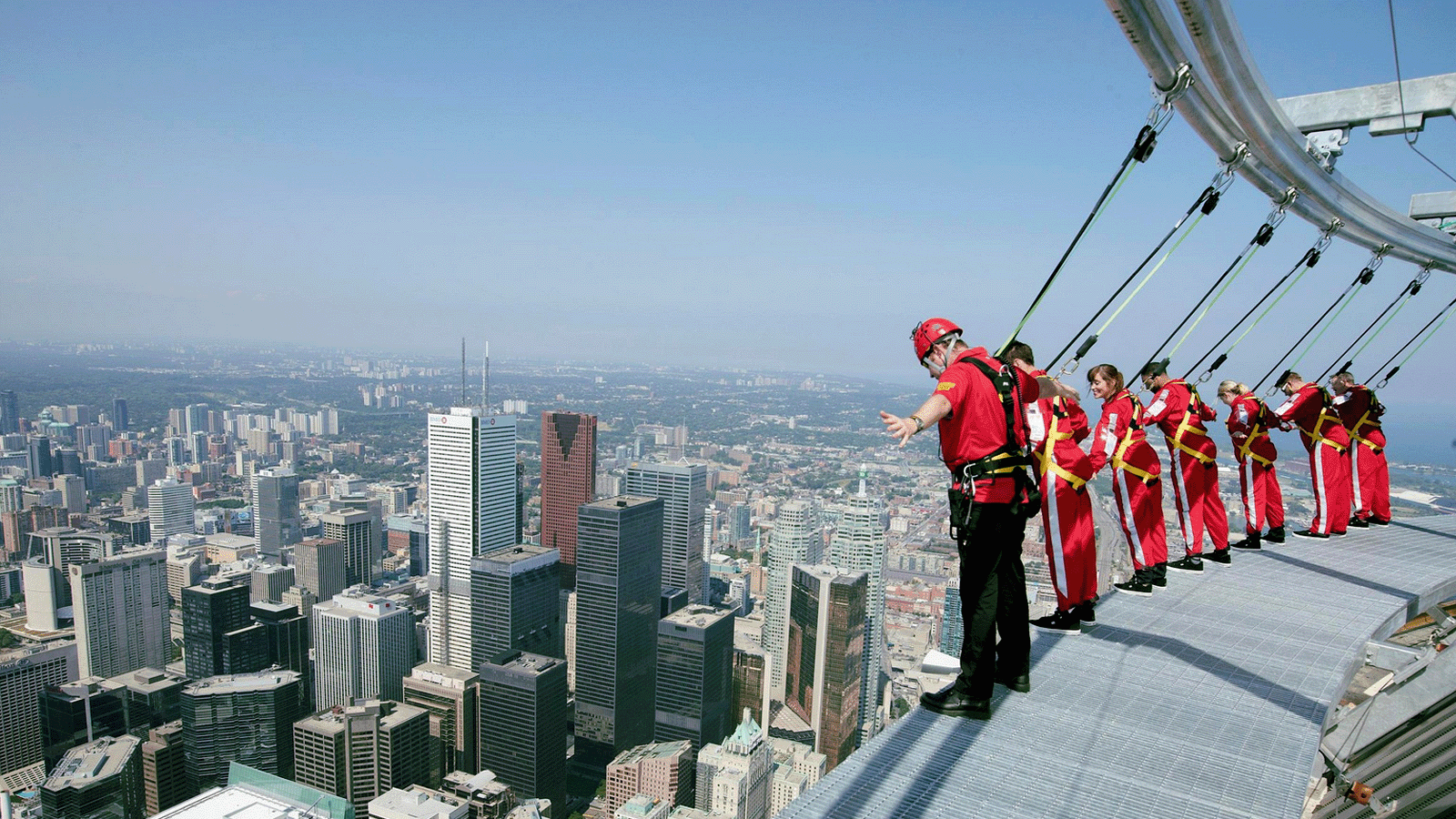 CN Tower EdgeWalk adventurers walking hands-free around the exterior edge 116 storeys above Toronto