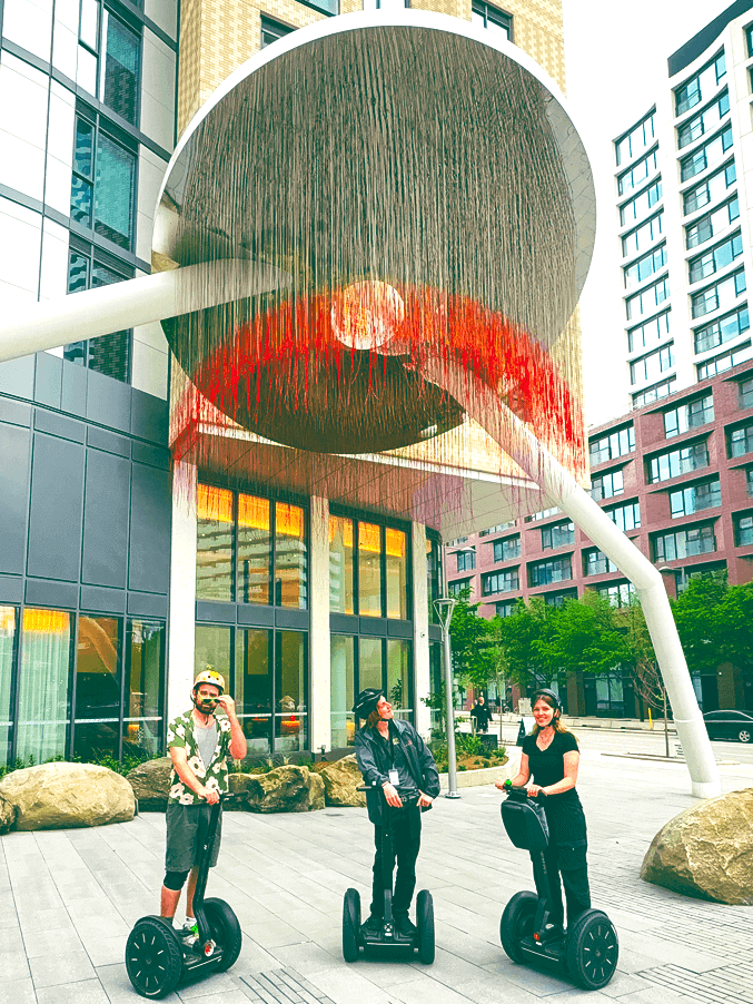 Three tourists on Segways exploring modern Canary District architecture and public art during Go Tours Canada's Toronto Segway tour.