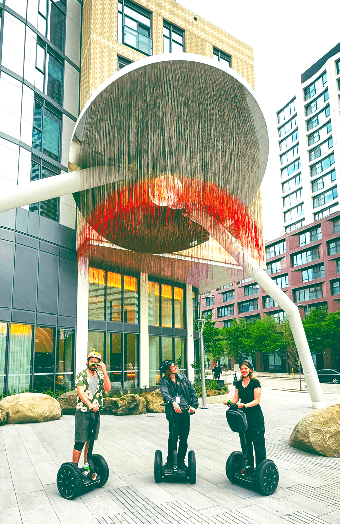Three tourists on Segways exploring modern Canary District architecture and public art during Go Tours Canada's Toronto Segway tour.