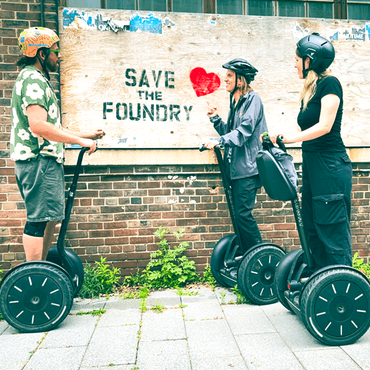 Segway tour participants viewing Save the Foundry mural in Toronto's historic Canary District during guided heritage tour.