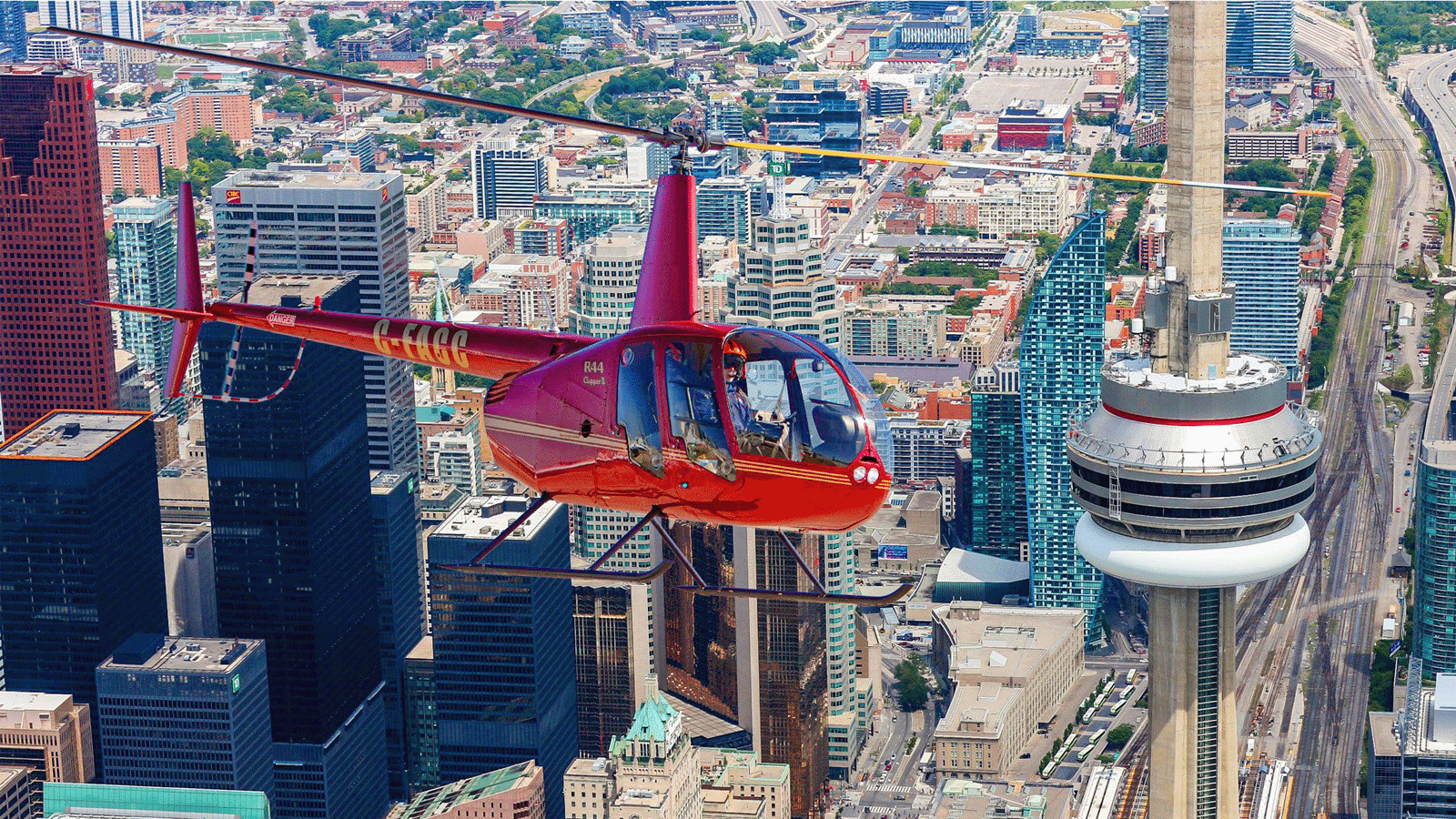 Helicopter flying over Toronto skyline with CN Tower and Lake Ontario aerial perspective