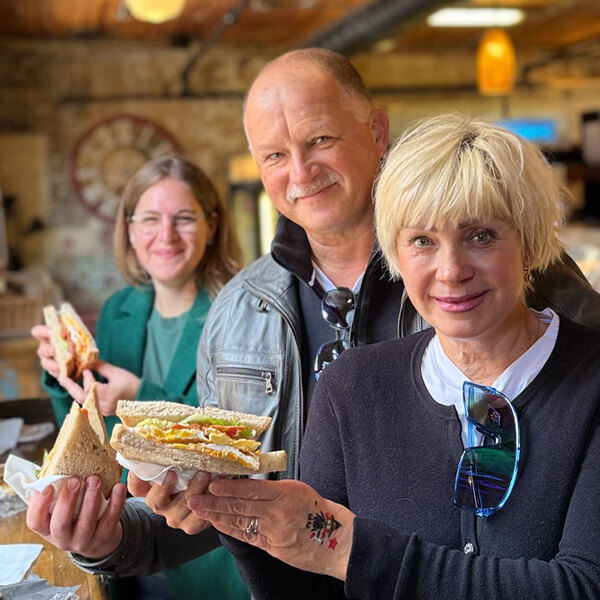 Three guests holding breakfast sandwiches on the Distillery District Breakfast Tour